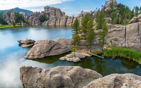 body of water at custer state park surrounded by rocks and trees