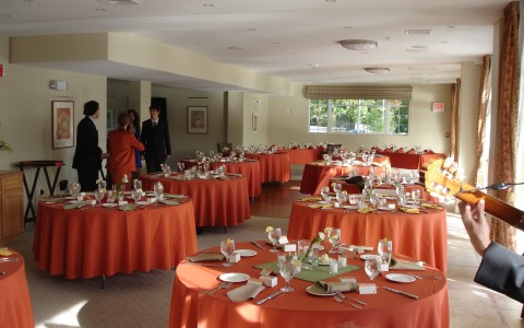 event space set up with orange clothed banquet tables