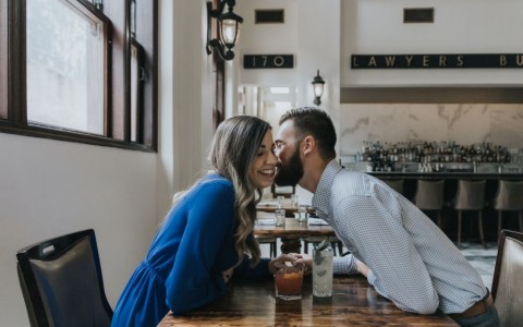 couple kissing over cocktails