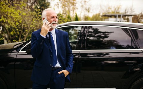 man standing outside of the car on the phone