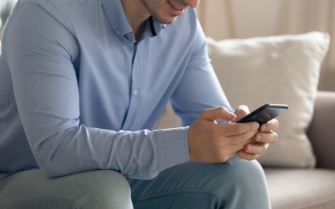 man in blue shirt looking at his phone
