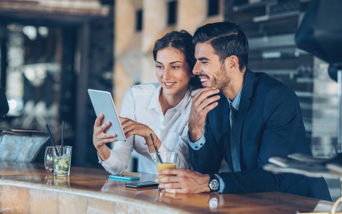 man and woman sitting at bar looking at tablet