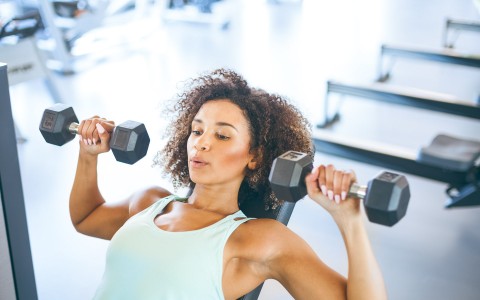 woman using weights above her shoulder