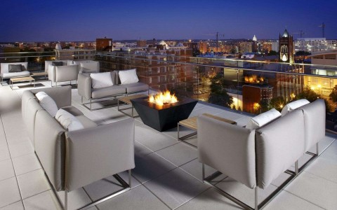 hotel rooftop with seating and fire pit with view of city