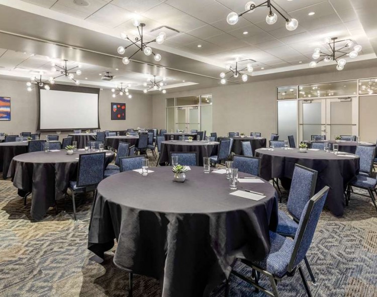 large event space with round tables and projector screen