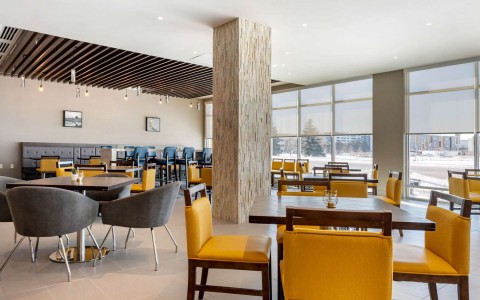 dining area with yellow and dark brown chairs tables and booths in the back