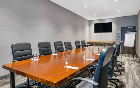 meeting room with brown table and black chairs with a tv in the front of the room
