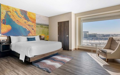 Guest room with one bed a small round table and a large chair next to it 