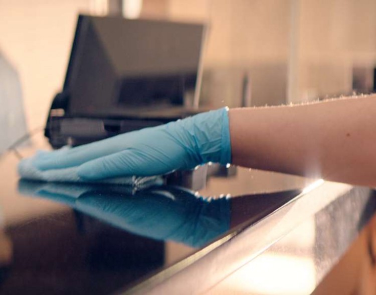 hand wearing blue glove cleaning counter