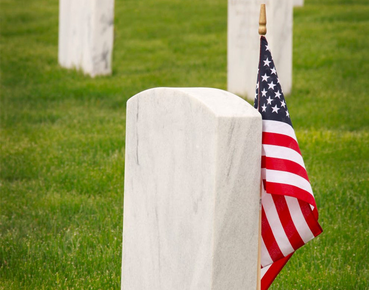 headstone and american flag in cemetery