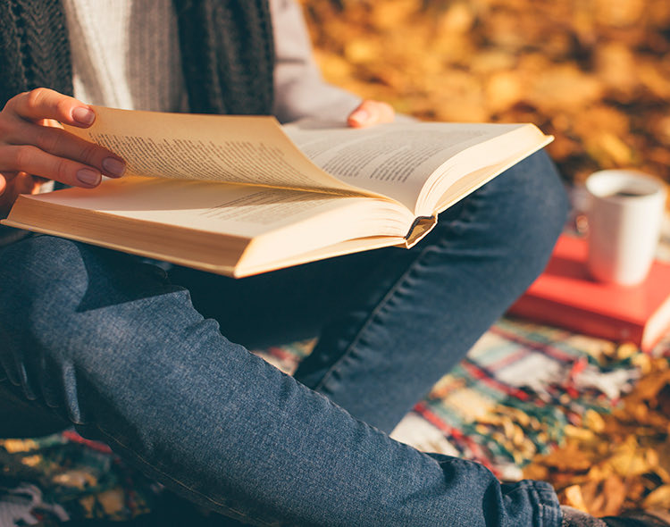 person sitting down outside and reading a book