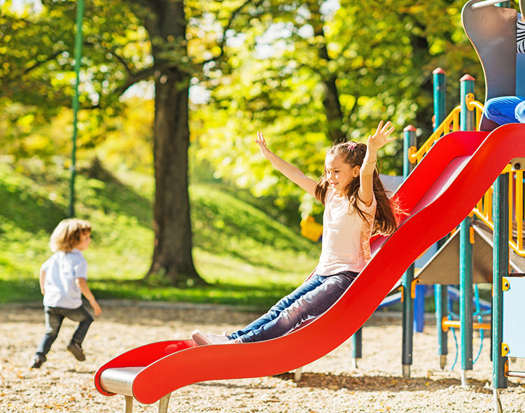 young girl going down red slide in park