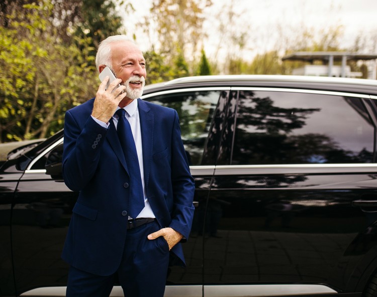 man in suit standing outside of car on the phone