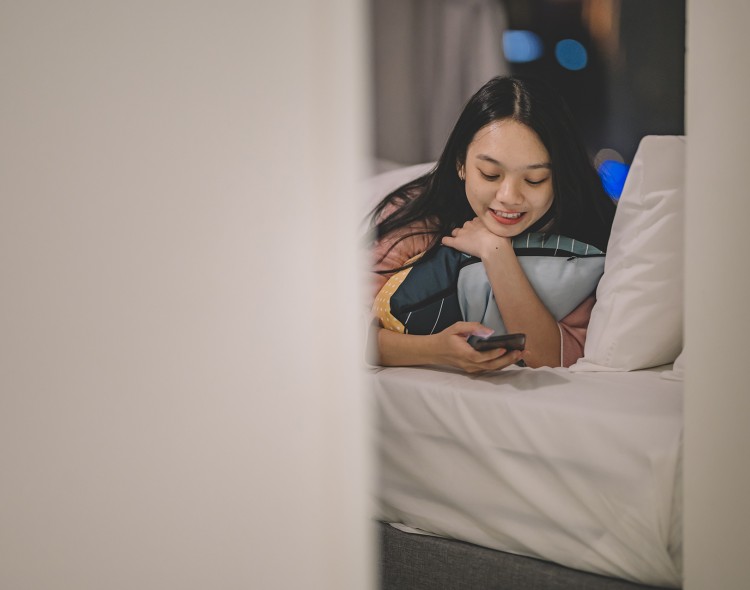 girl laying on bed looking at phone