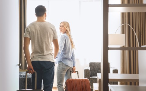 couple arriving to their hotel room with carry-ons