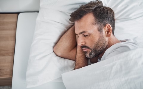 man sleeping in bed in white sheets