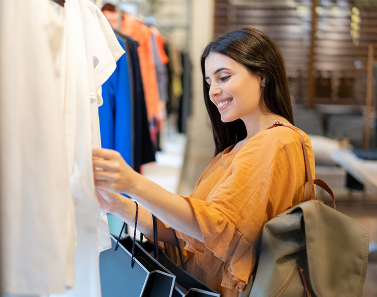 woman with orange top looking through clothes at a store