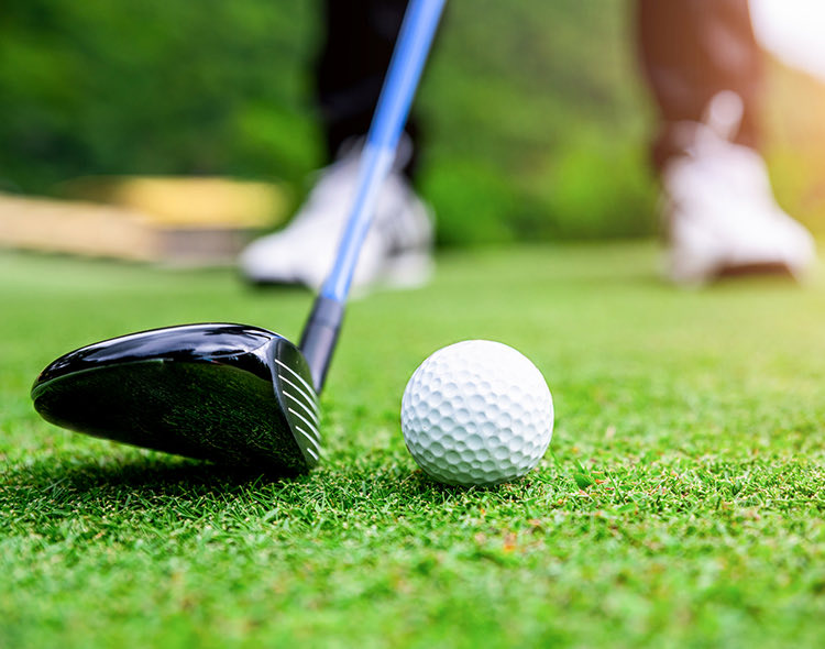 a golf club about to hit a golf ball