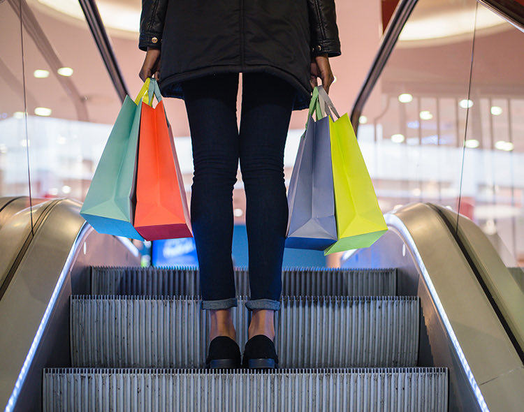 woman on an escalator carrying lots of shopping bags