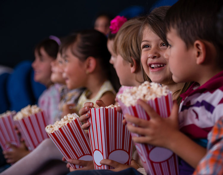 a group of little kids eating popcorn at a show