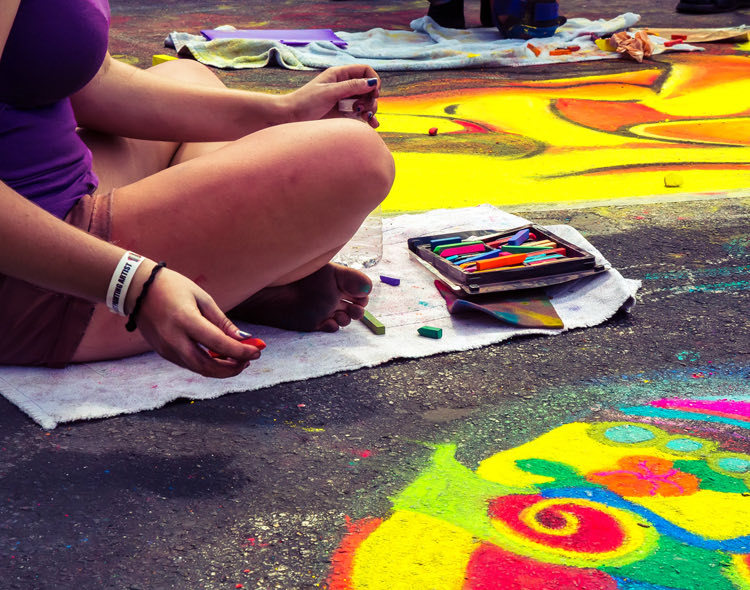 a woman drawing on the sidewalk