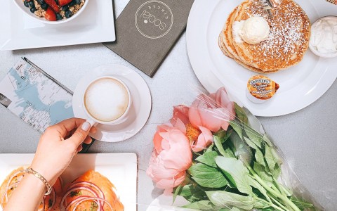 overhead shot of pancakes, lox, fruit and granola, coffee, and flowers
