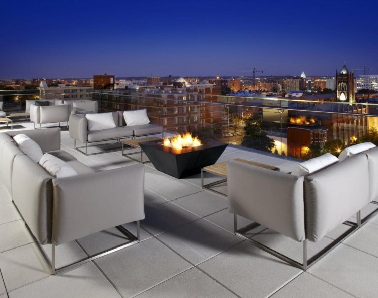 hotel rooftop with seating and fire pit with view of city