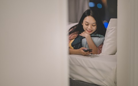 woman laying down in bed while on phone