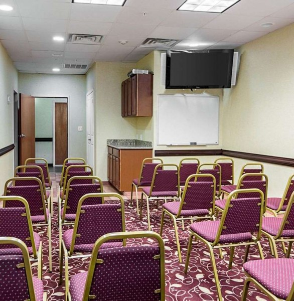 meeting room set up with rows of chairs and a tv on the wall