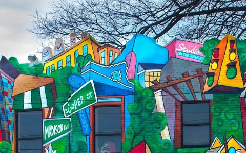 colorful murals of storefronts and street signs 