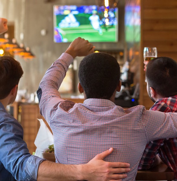 three friends watching a sports game at a bar
