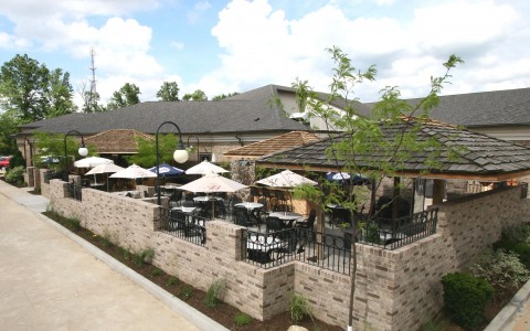exterior view of dining patio with white patio umbrellas and trees