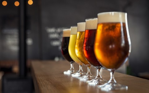 row of different colored beer flight