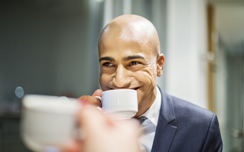 man smiling sipping cup of coffee
