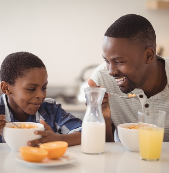 father and son eating cereal for breakfast with orange juice