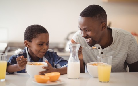 father and son eating breakfast together with juice on the table