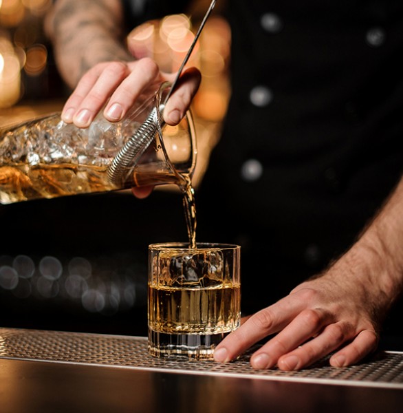 bartender pouring a glass of whisky