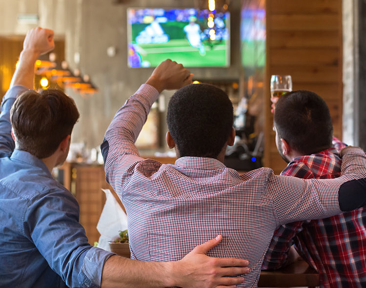 three friends watching a sports game at a bar