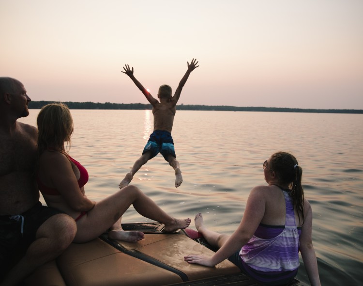 family playing in lake with boy jumping in