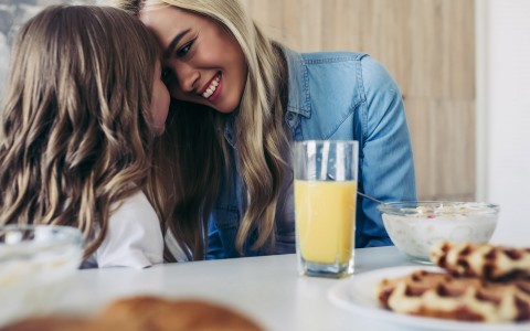 mother and daughter with foreheads together at breakfast table