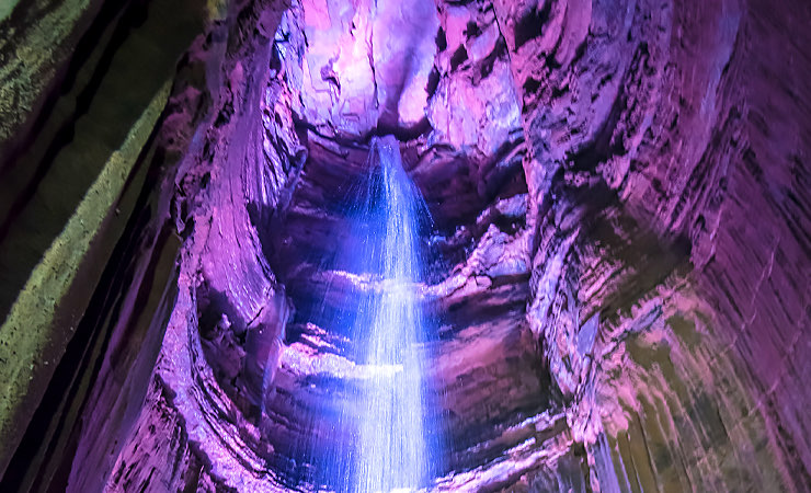 waterfall inside rocks with glowing purple-pink light