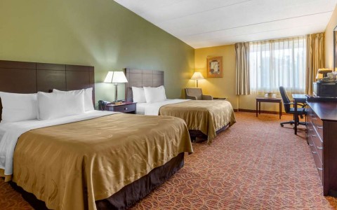 room with two double beds, tv, and desk