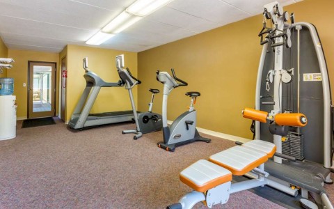gym with treadmill, two stationary bikes, and weight machine
