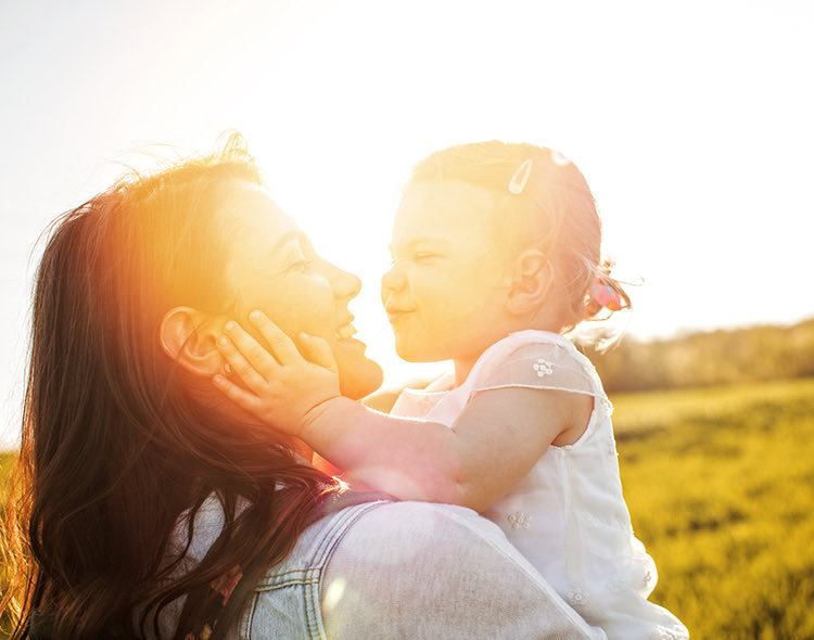 mother holding daughter in arms outside