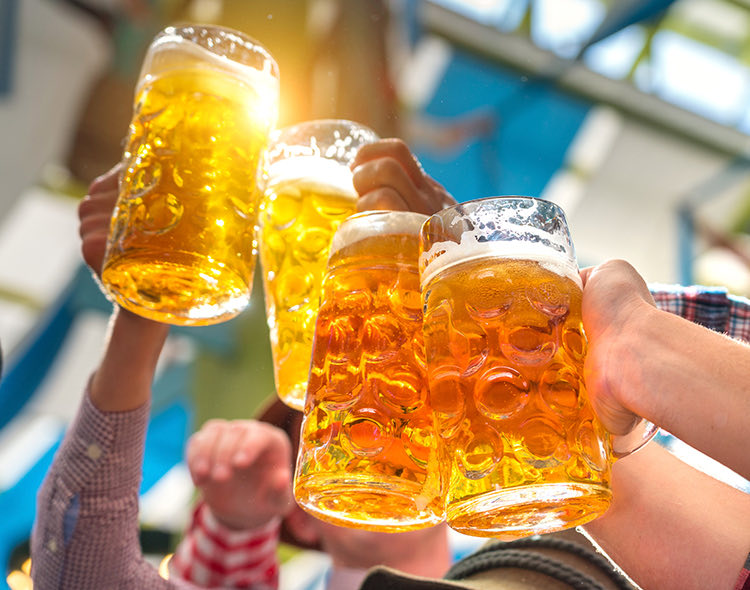 group of people raising up their large beer glasses to cheers