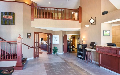 Hotel lobby with front desk, business center, and staircase up to 2nd floor