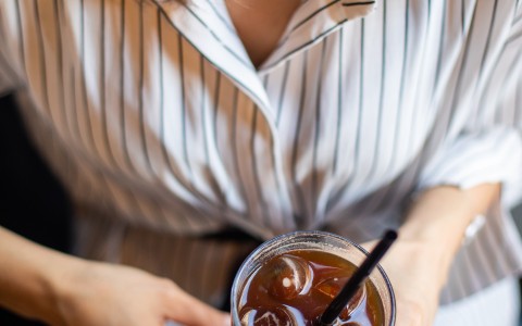 top shot of woman holding iced cup of coffee