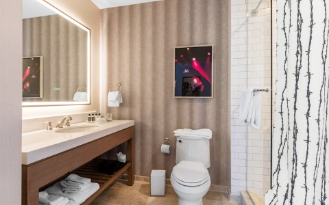 View of a hotel washroom with features as a toilet, rectangular stylish mirror and some towels