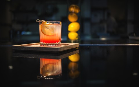 Closeup view of a red cocktail  and four limes in the background