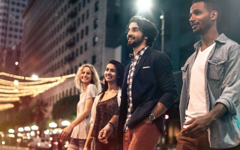 Two young ladies and well dressed guys walking in the street during the night